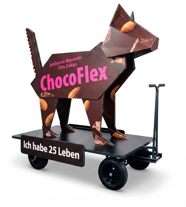 Pappkatze auf Transportwagen als Werbefigur f&uuml;r ChocoFlex Schokolade mit ger&ouml;steten Mandeln und Claim Ich habe 25 Leben