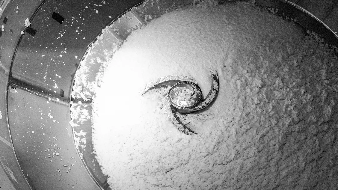 Runder Metallmischer mit spiralf&ouml;rmigem R&uuml;hrwerk durchmischt wei&szlig;en Papierbrei, Detailansicht des Produktionsprozesses