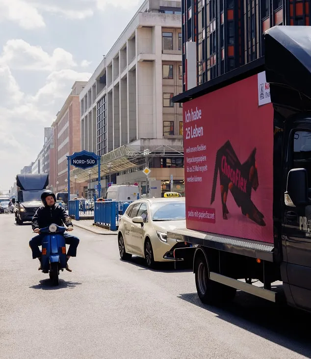 Werbetruck mit pinker "Pack's mit Papier"-Fl&auml;che und Slogan "Ich habe 25 Leben" f&auml;hrt im berliner Regierungsviertel neben einem Rollerfahrer